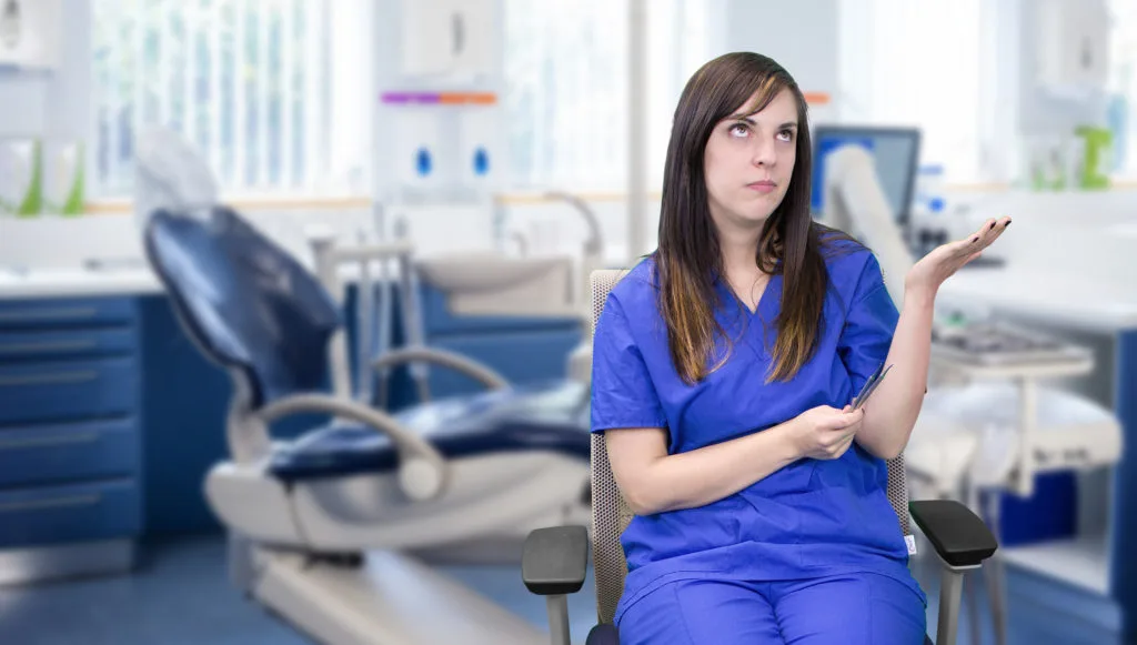 A dental hygienist performing a cleaning on a patient in a dental chair.