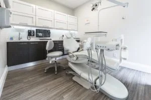 A dental chair positioned in an examination room with medical equipment nearby.