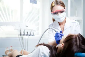Dental hygienist performing oral examination on a patient.