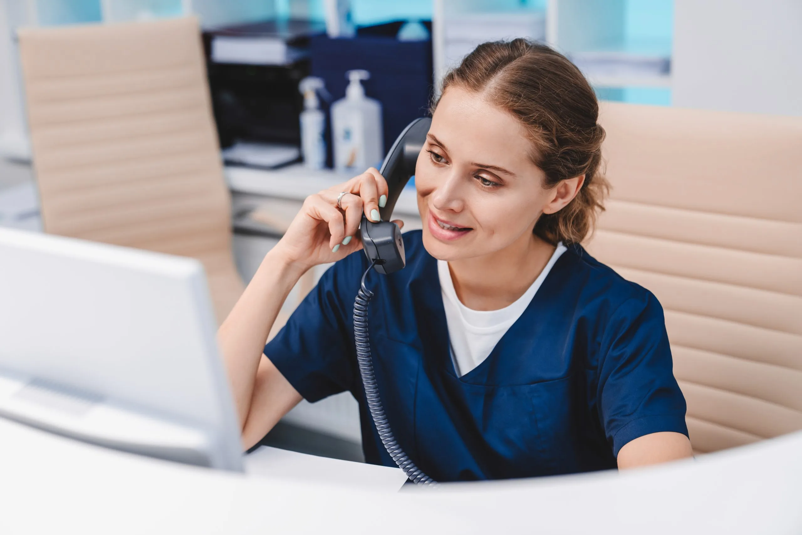 A friendly receptionist smiling while working at a dental office front desk.