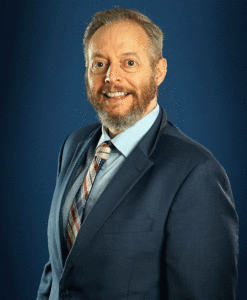 A professional man smiling in a modern office setting.