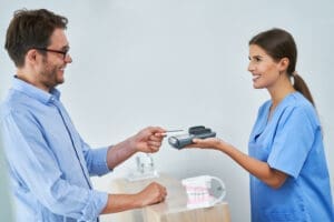 Dental front desk staff assisting a patient.
