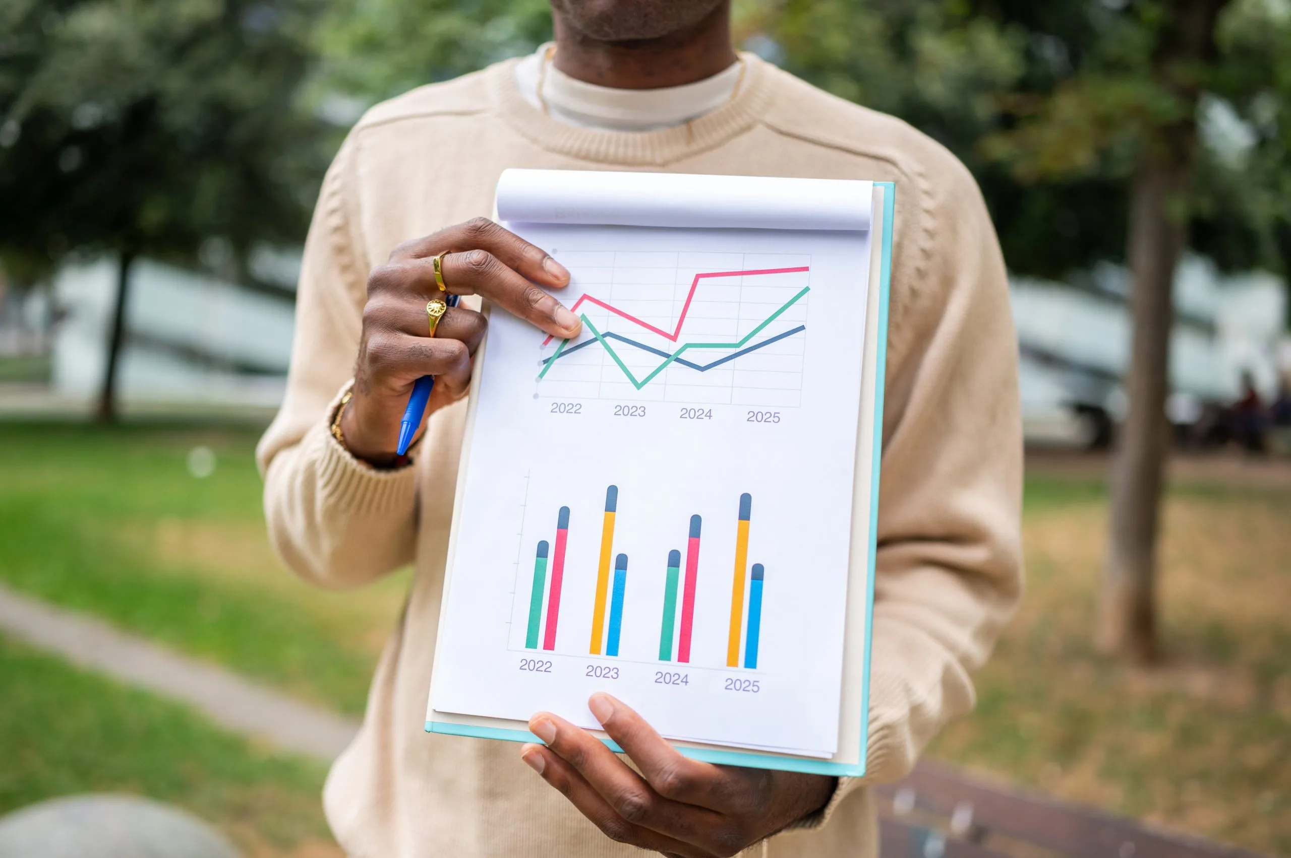 Person holding a paper with a pie chart and bar charts.