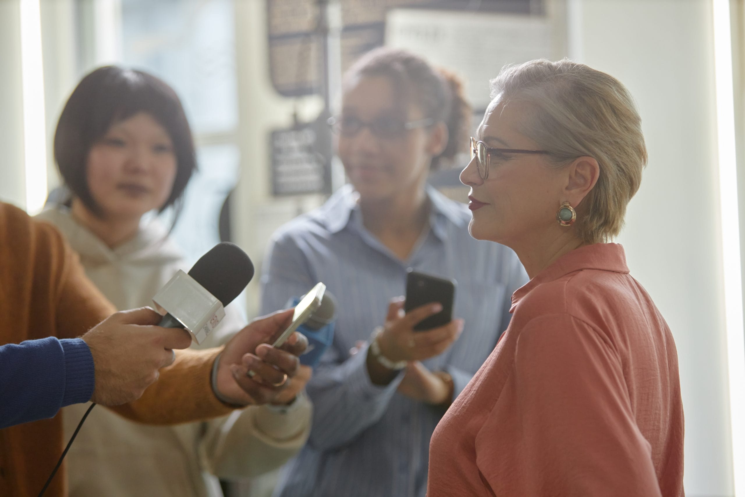 A professional looking women in front of people holding microphones at her