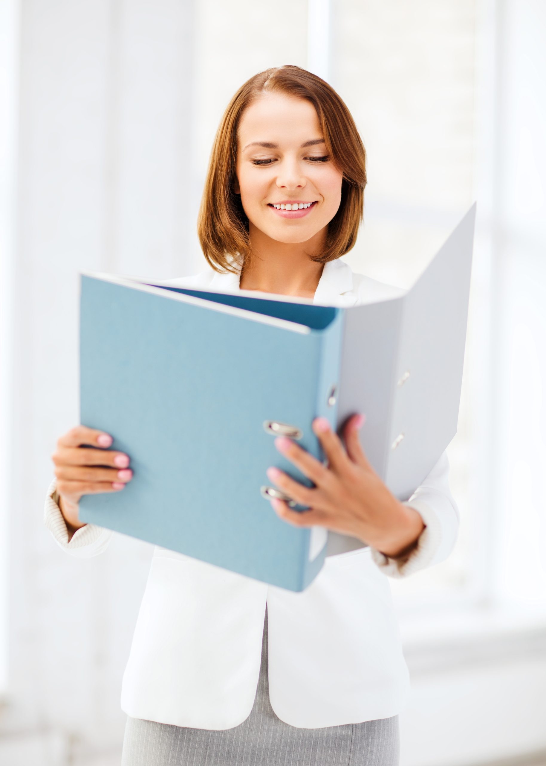 Woman holding a blue binder, in a professional work setting.